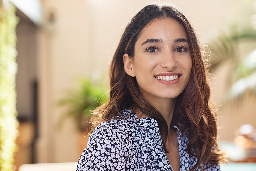 Closeup face of happy smiling young woman. Portrait of beautiful latin girl looking at camera. Confident casual girl sitting at cafeteria.