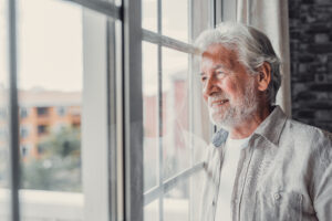 Older man looks out window