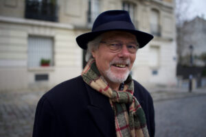 smiling grey haired man in black hat