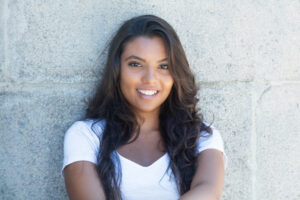 Latin american woman smiling against wall